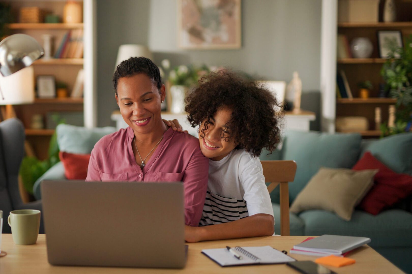 Mother and child smiling at laptop together.