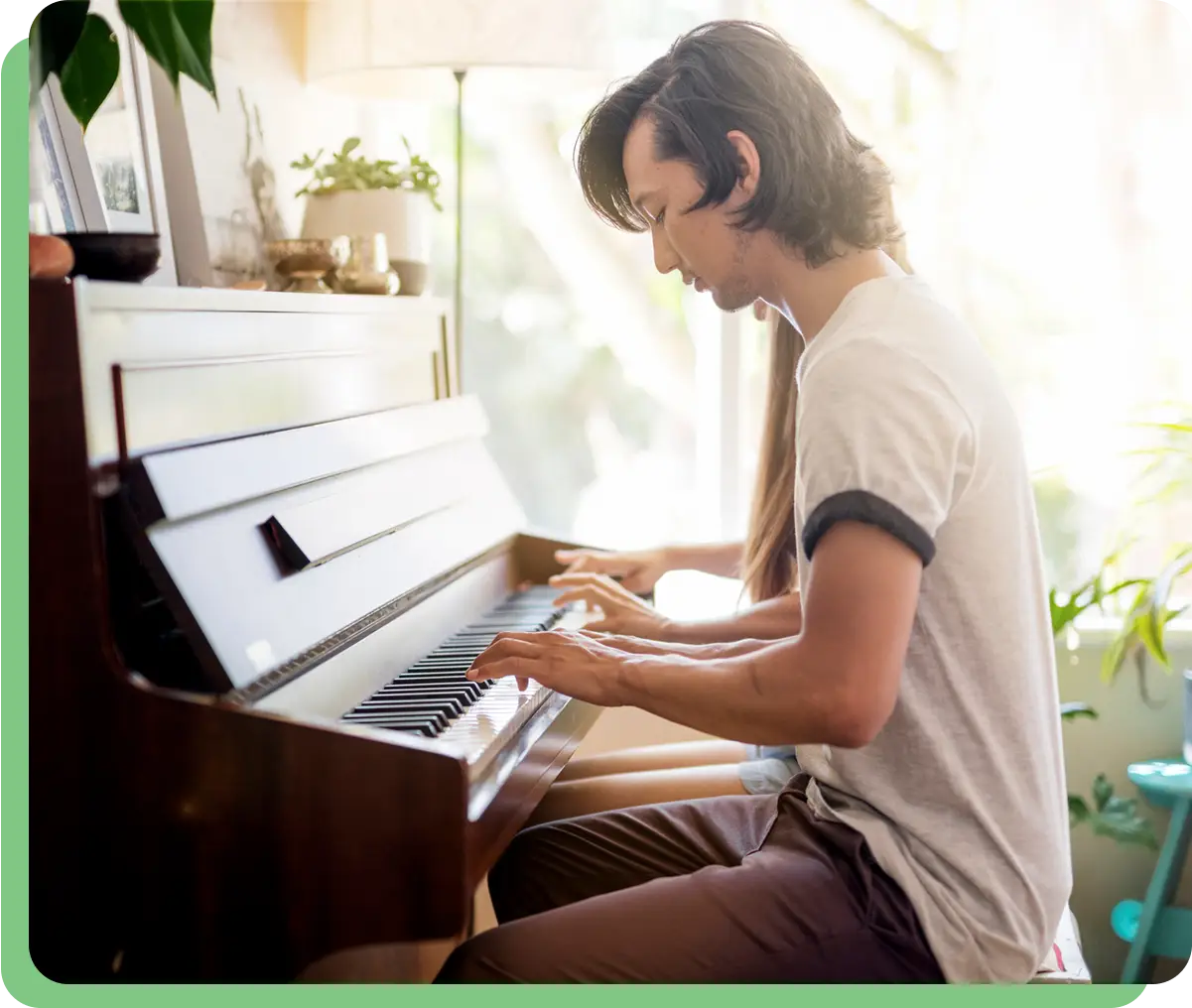 Person playing piano in sunlit room.