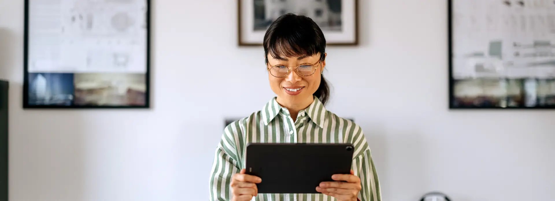 Woman smiling while looking at a tablet.