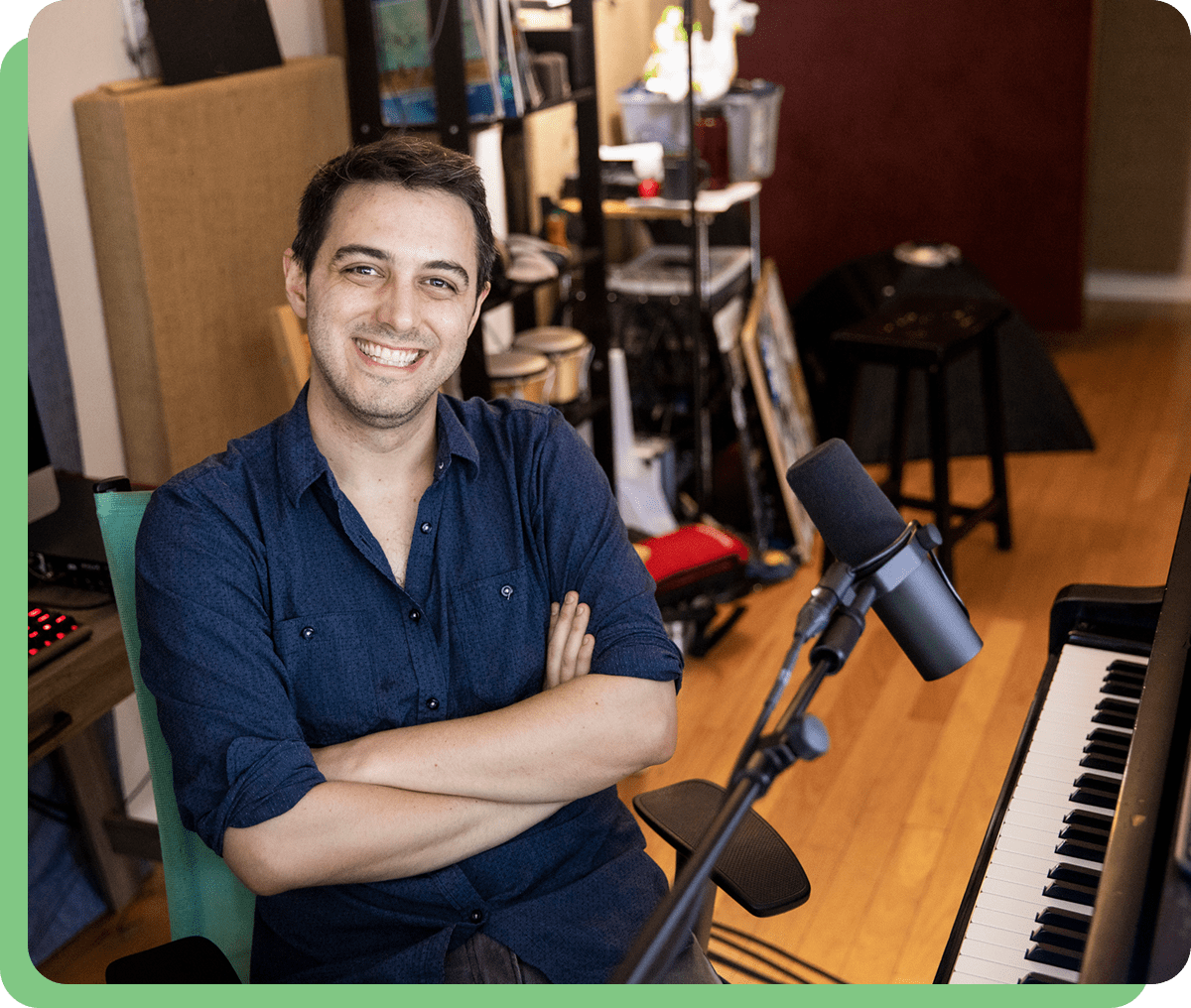 Man smiling, seated at piano with microphone.