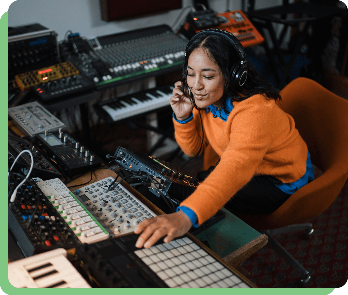 Woman in orange sweater using music equipment.