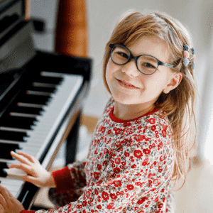 Child smiling while playing the piano keys.