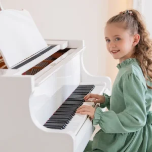 Girl playing a white piano, smiling happily.